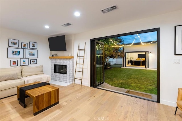 living room with visible vents, wood finished floors, a fireplace with flush hearth, and recessed lighting