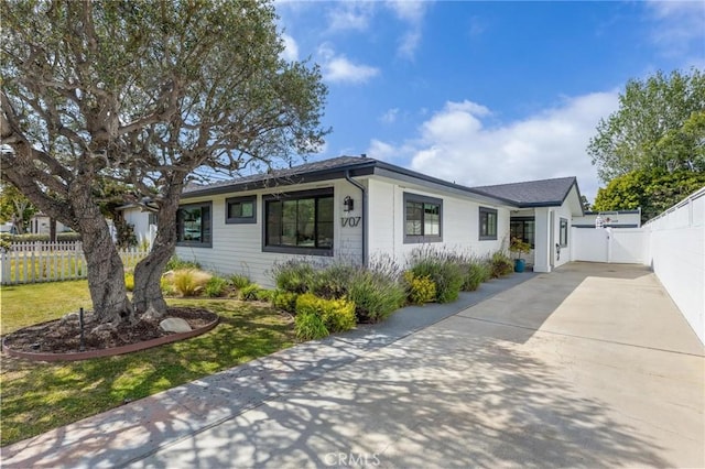 ranch-style home with driveway, fence, and a gate