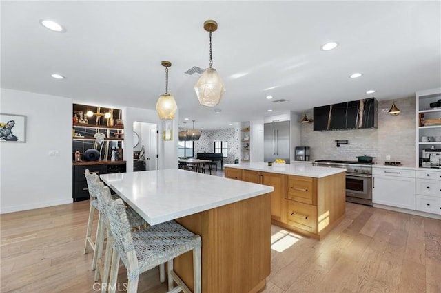 kitchen with range hood, premium appliances, visible vents, a large island, and tasteful backsplash