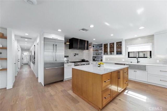 kitchen with stainless steel built in refrigerator, visible vents, a sink, open shelves, and decorative backsplash