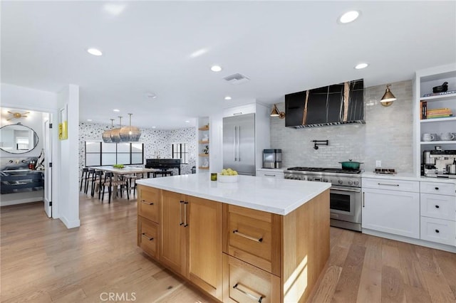 kitchen featuring open shelves, visible vents, wall chimney exhaust hood, a center island, and stainless steel range