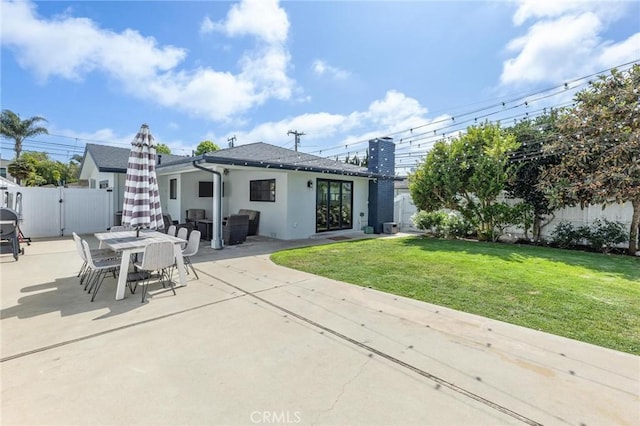 back of property featuring a gate, stucco siding, fence, a lawn, and a patio area