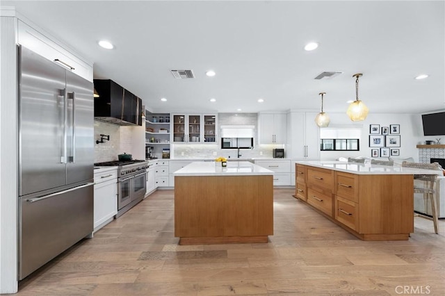 kitchen featuring a sink, tasteful backsplash, visible vents, a center island, and high end appliances