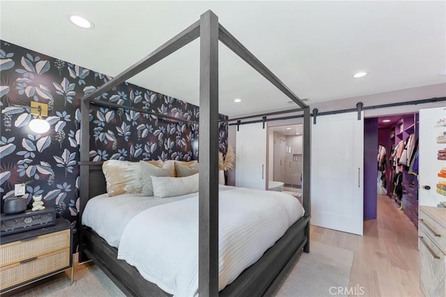 bedroom featuring recessed lighting, a barn door, and wood finished floors