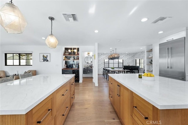 kitchen featuring a large island, open floor plan, visible vents, and built in refrigerator