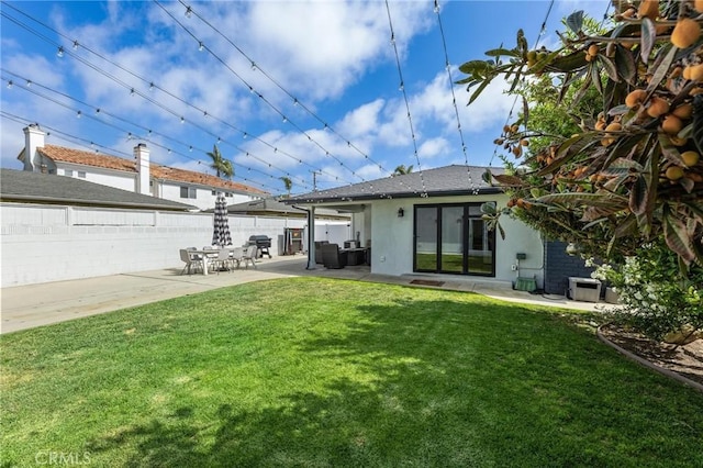 back of property featuring fence, stucco siding, a patio area, and a lawn