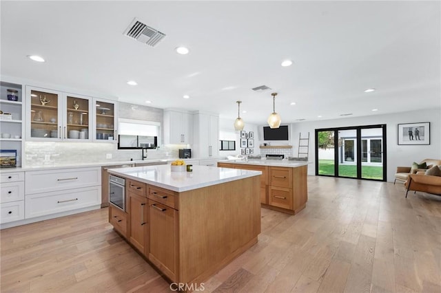 kitchen with visible vents, light wood-style flooring, decorative backsplash, open floor plan, and a center island