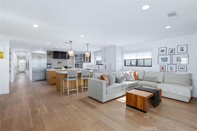living room with recessed lighting, light wood-style floors, and visible vents