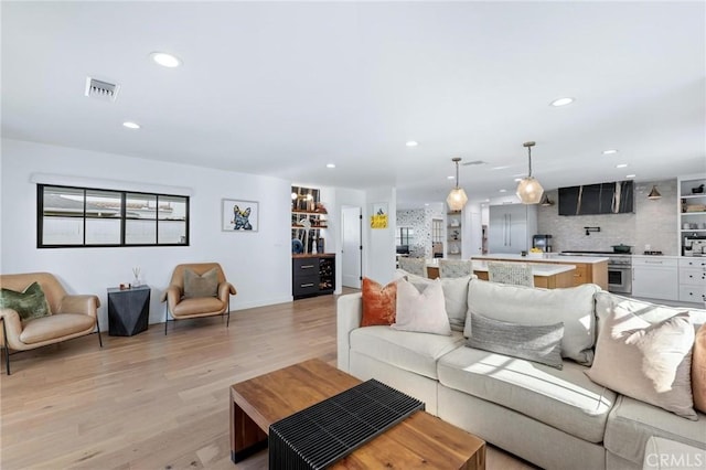 living area featuring light wood-style floors, baseboards, visible vents, and recessed lighting