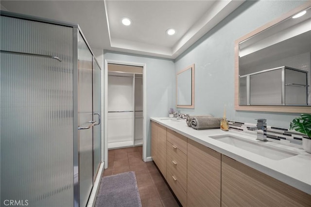 bathroom featuring a shower stall, tile patterned floors, double vanity, and a sink