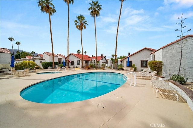 community pool featuring a hot tub, a patio, and a residential view