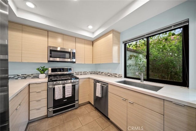 kitchen featuring light countertops, light brown cabinetry, appliances with stainless steel finishes, and a sink