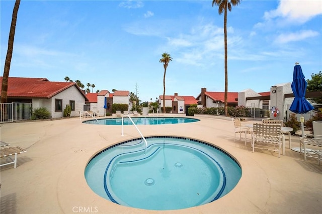 pool featuring a patio, a community hot tub, fence, and a residential view