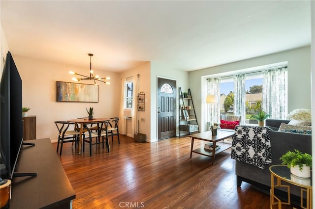 living area featuring an inviting chandelier, dark wood finished floors, and baseboards