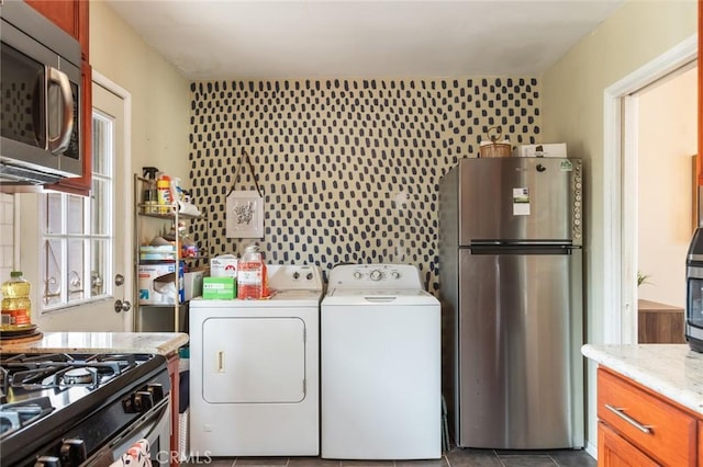 washroom with independent washer and dryer, dark tile patterned floors, and laundry area
