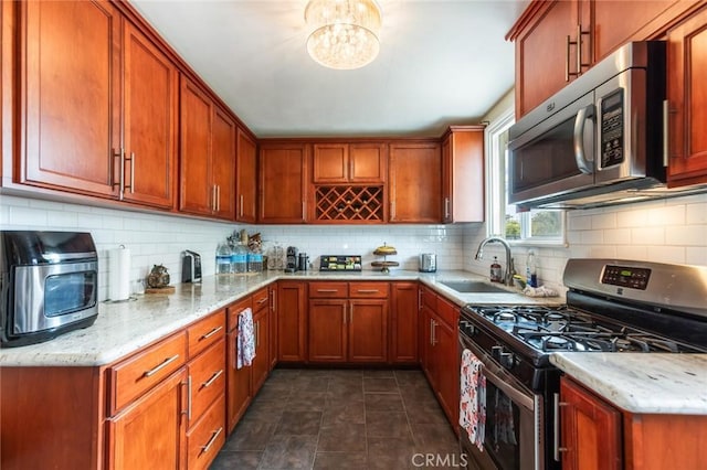 kitchen featuring a sink, backsplash, light stone countertops, and stainless steel appliances