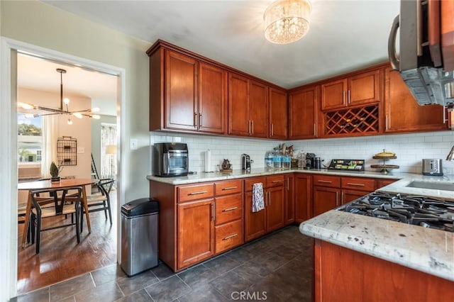 kitchen featuring brown cabinetry, backsplash, and a chandelier