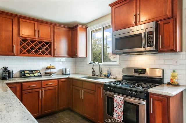 kitchen featuring a sink, appliances with stainless steel finishes, brown cabinetry, and backsplash