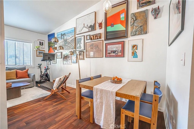 dining room with baseboards, lofted ceiling, and wood finished floors