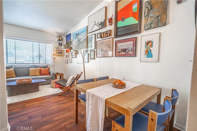 dining area featuring vaulted ceiling and wood finished floors
