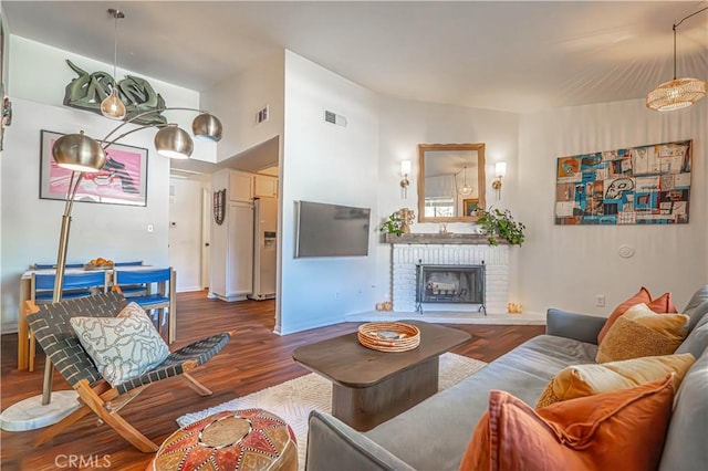 living room with baseboards, a fireplace, wood finished floors, and visible vents