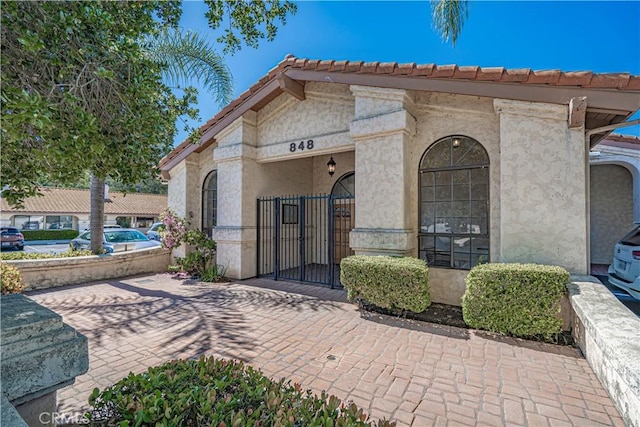 view of front of home featuring a gate, stucco siding, and a tiled roof