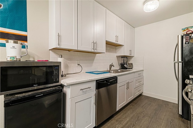 kitchen with appliances with stainless steel finishes, a sink, white cabinetry, tasteful backsplash, and dark wood-style floors