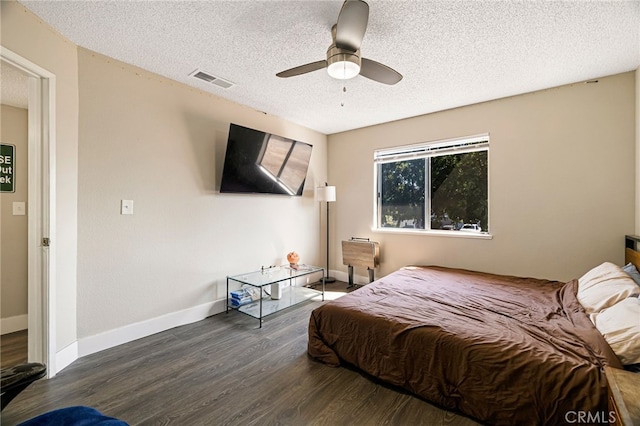 bedroom featuring ceiling fan, a textured ceiling, baseboards, wood finished floors, and visible vents