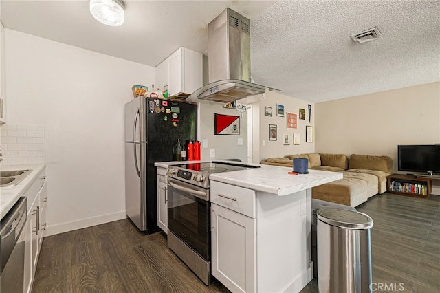 kitchen with visible vents, dark wood-style flooring, a peninsula, range hood, and stainless steel appliances