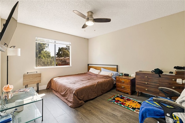 bedroom with a textured ceiling, ceiling fan, and wood finished floors