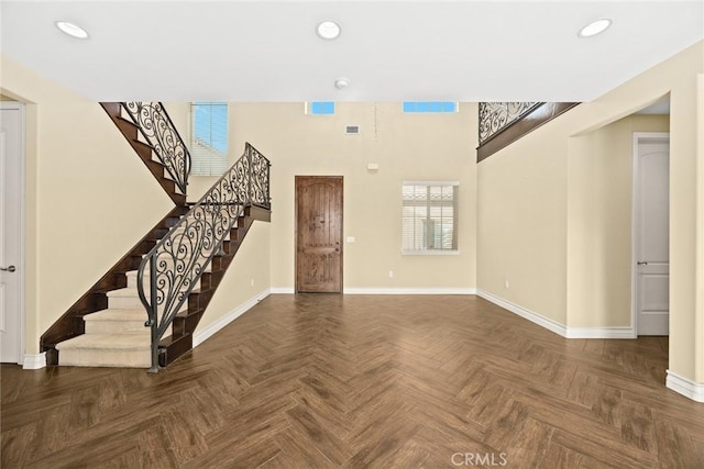 unfurnished living room featuring baseboards, recessed lighting, a high ceiling, and stairway