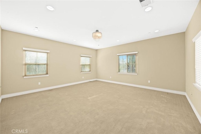 empty room featuring baseboards, a wealth of natural light, light carpet, and visible vents