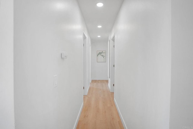 hall with baseboards, light wood finished floors, and recessed lighting