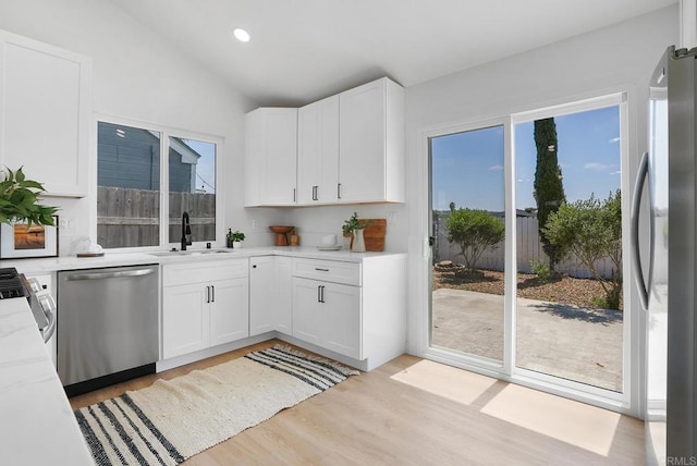 kitchen with a sink, appliances with stainless steel finishes, plenty of natural light, and light wood-style floors