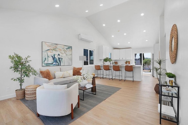 living area featuring a wall unit AC, high vaulted ceiling, baseboards, light wood-style floors, and recessed lighting