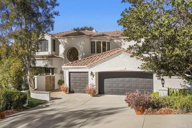 mediterranean / spanish home with an attached garage, stucco siding, a tile roof, and concrete driveway