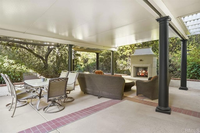 view of patio featuring a lit fireplace and outdoor dining space