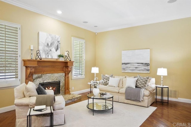 living room with crown molding, a premium fireplace, baseboards, and wood finished floors
