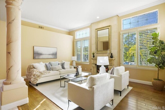 living room with visible vents, crown molding, baseboards, ornate columns, and hardwood / wood-style floors