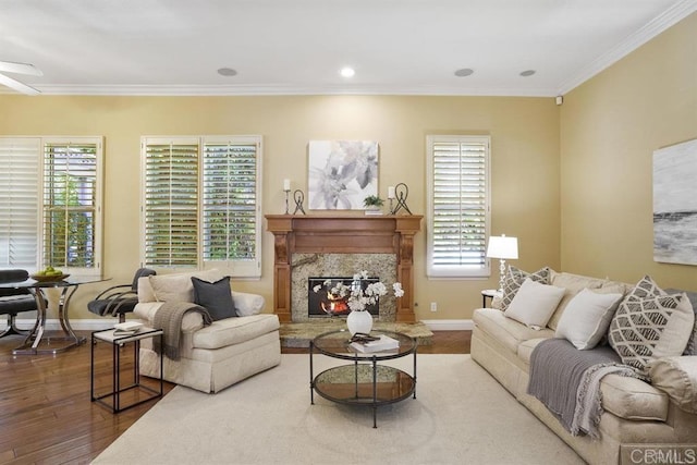 living area featuring baseboards, ornamental molding, wood finished floors, and a healthy amount of sunlight