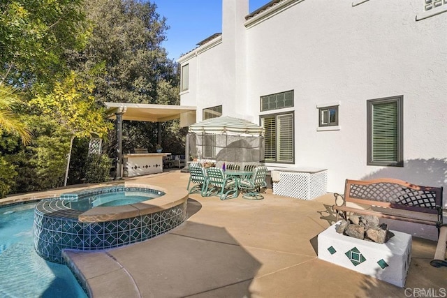 exterior space with an outdoor kitchen, a pool with connected hot tub, and outdoor dining space