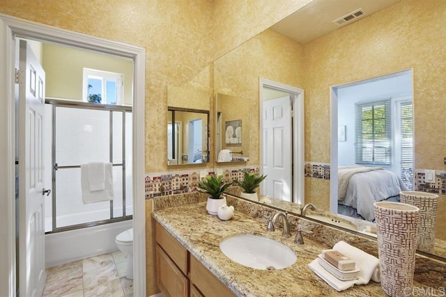ensuite bathroom featuring visible vents, vanity, toilet, shower / bath combination with glass door, and ensuite bathroom