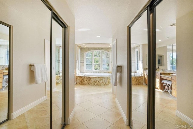 corridor featuring baseboards and light tile patterned flooring