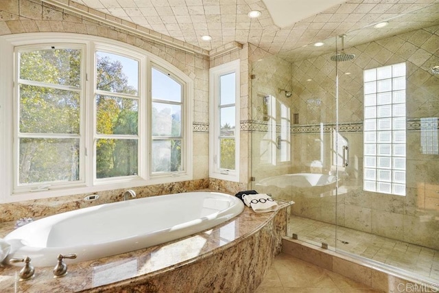 bathroom featuring a garden tub, a healthy amount of sunlight, and a shower stall