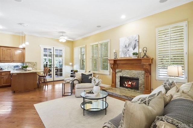 living area featuring crown molding, a ceiling fan, light wood finished floors, and a fireplace