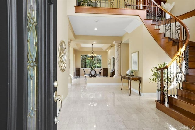 entrance foyer with a raised ceiling, baseboards, a notable chandelier, and stairway