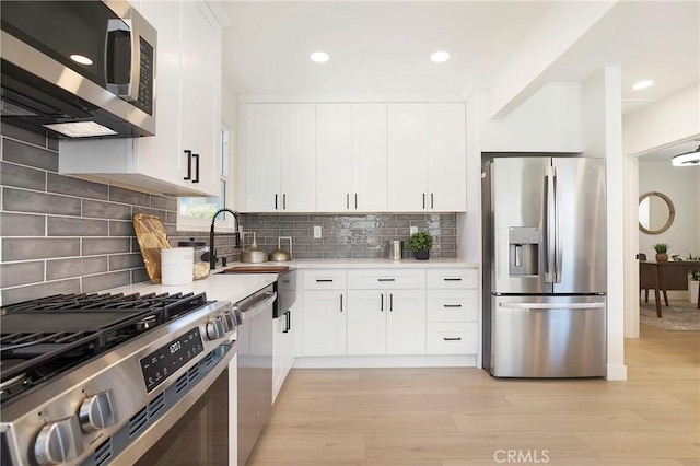 kitchen with light countertops, light wood-style flooring, white cabinetry, and stainless steel appliances