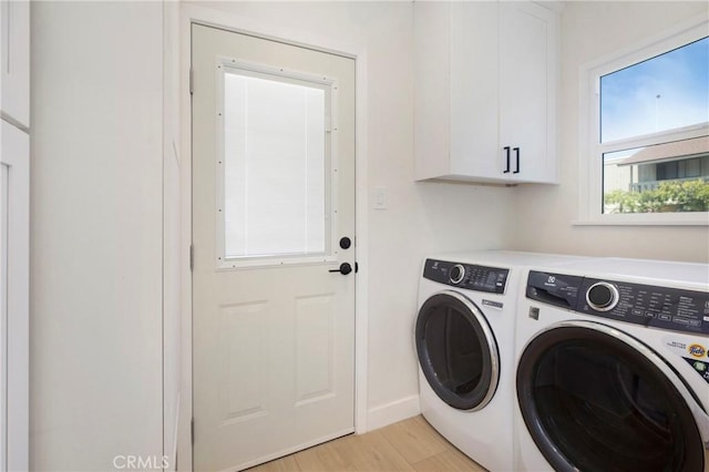 laundry room with baseboards, light wood-type flooring, cabinet space, and washing machine and clothes dryer