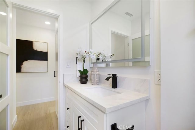 bathroom with vanity, visible vents, wood finished floors, baseboards, and recessed lighting