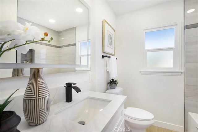 bathroom with recessed lighting, a healthy amount of sunlight, toilet, and vanity